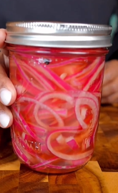 A person holding onto a jar of pickled onions