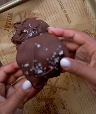 A person holding a chocolate covered doughnut