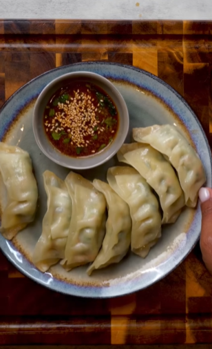 A plate of dumplings with dipping sauce.