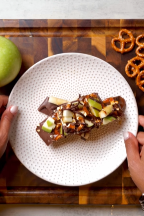 A white plate topped with pieces of chocolate covered fruit.