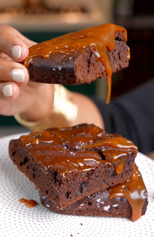 A person holding onto some brownies with caramel on top