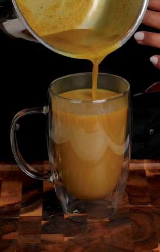 A person pouring liquid into a glass mug.