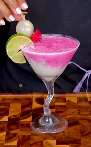 A pink drink with lime and ice in it.