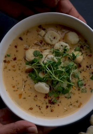 A bowl of soup with mushrooms and greens.