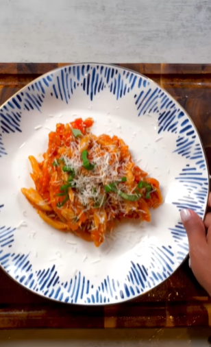 A plate of pasta with tomato sauce and parmesan cheese.