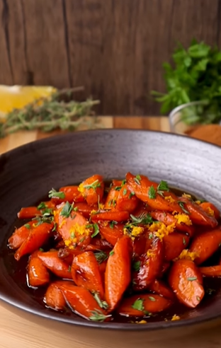 A bowl of carrots with lemon and herbs.