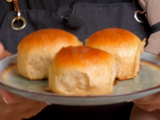 Three rolls of bread on a plate with a black apron.