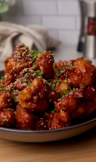 A plate of food with sesame chicken on it.