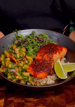 A bowl of food with salmon, rice and vegetables.