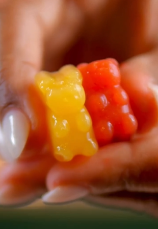 A person holding two gummy bears in their hands.