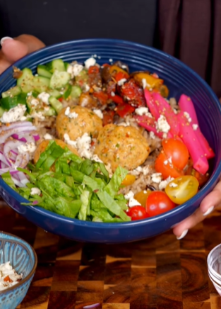 A bowl of food with meat, vegetables and rice.