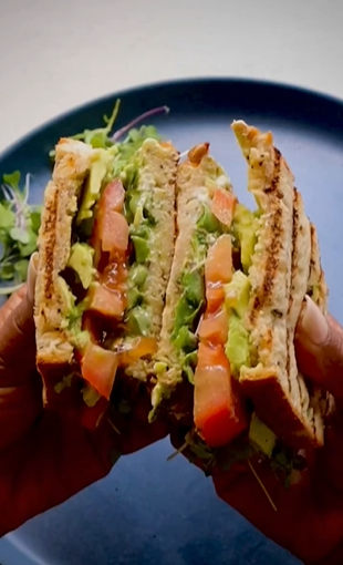 A person holding a sandwich cut in half.