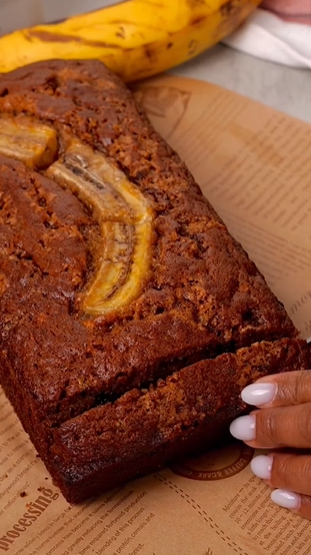 A person holding onto a banana bread with one half eaten.