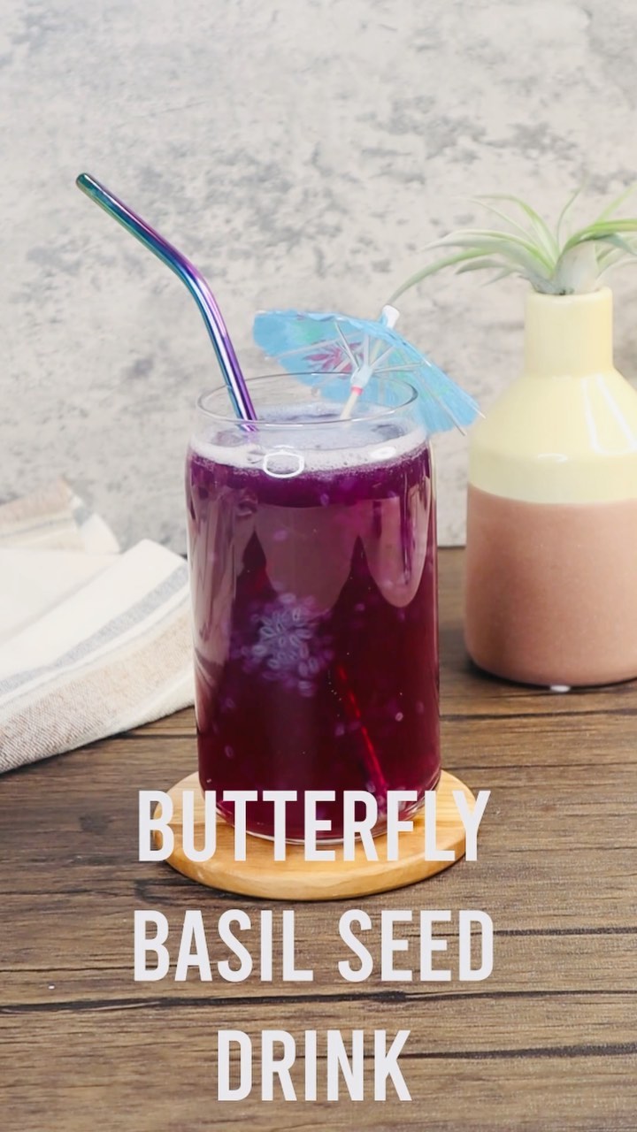 A glass of butterfly juice on a wooden table.