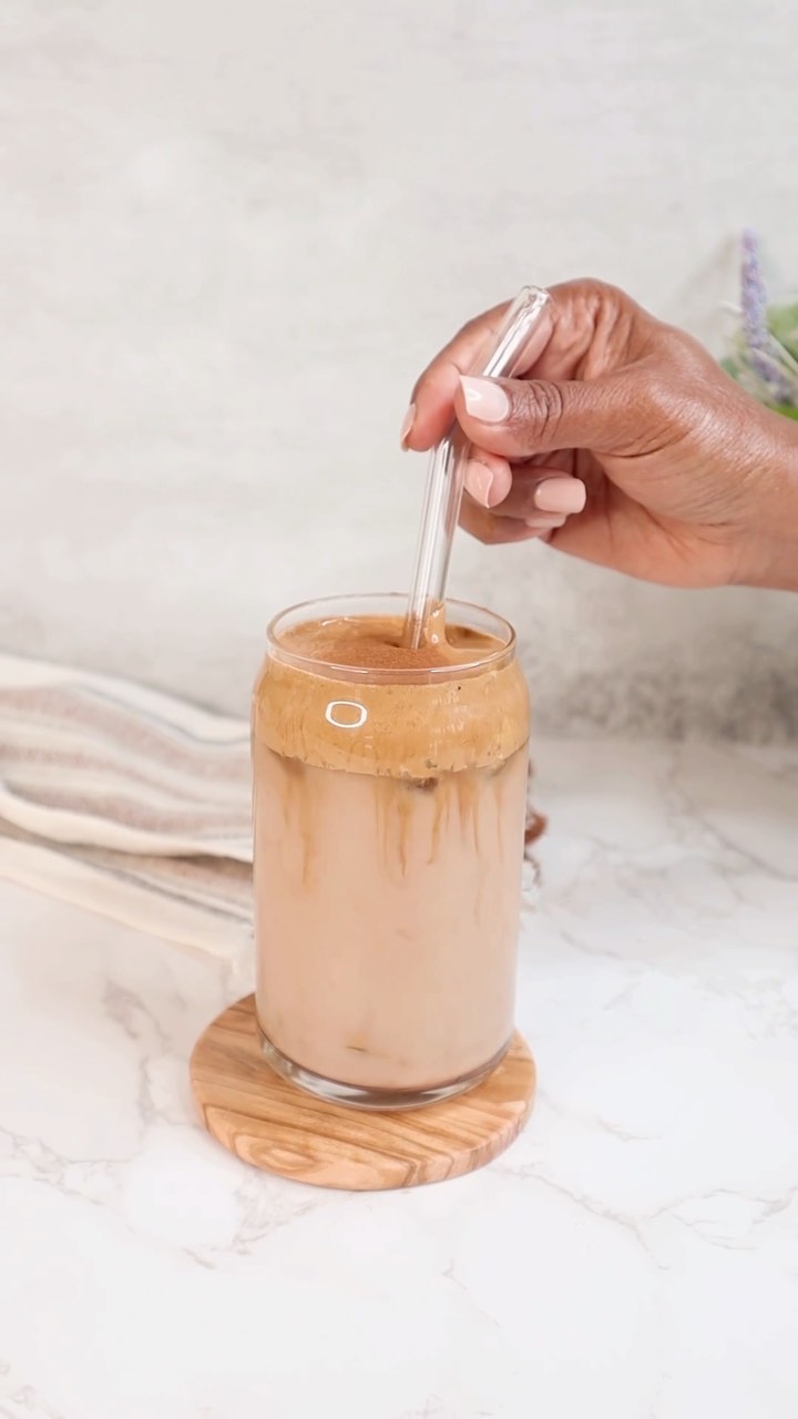 A person is stirring some liquid in a glass.