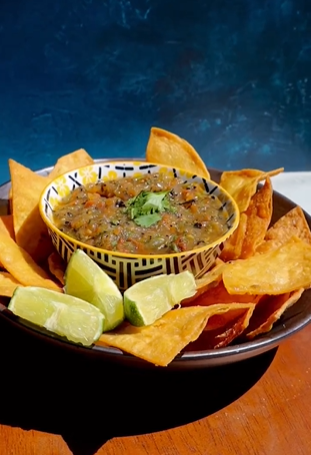 A bowl of salsa and tortilla chips on the table.