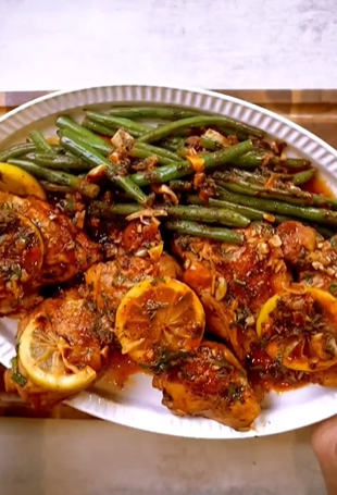 A plate of food with green beans and lemons.