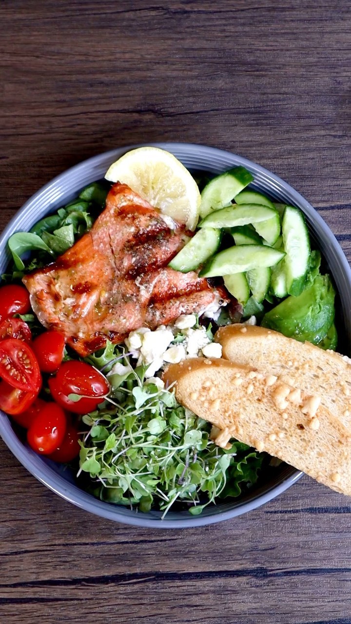 A bowl of food with meat, tomatoes and bread.