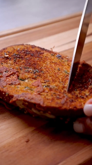 A person cutting into some food on top of a wooden table.