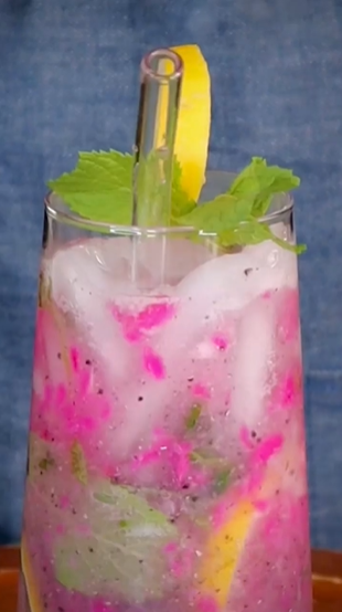 A glass of pink lemonade with mint and lemon.