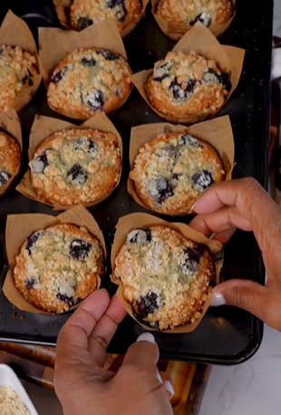 A person holding up some blueberry muffins