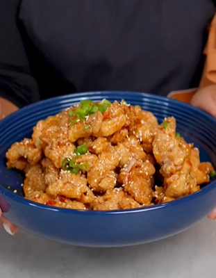 A person holding a bowl of food with meat.