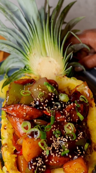 A pineapple with meat and vegetables on top of it.