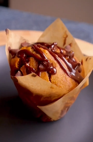 A muffin with chocolate sauce on top of it.