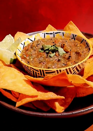 A bowl of salsa and tortilla chips on the table.