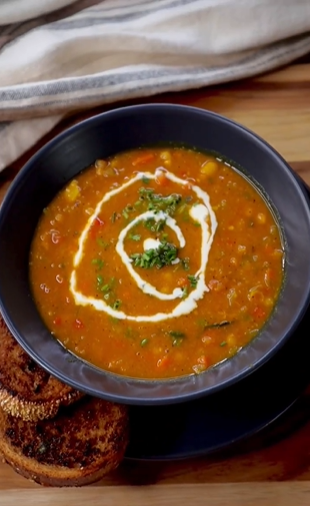 A bowl of soup with a swirl of sour cream.