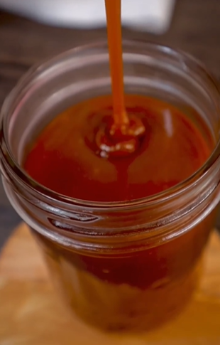 A jar of sauce is being poured into it.