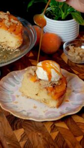 Upside-down peach cobbler cake with ice cream and caramel drizzle.